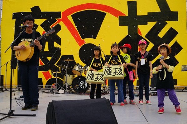歌手林生祥與女兒共同站在舞台上歌唱，為廢核基金募款小天使打廣告。